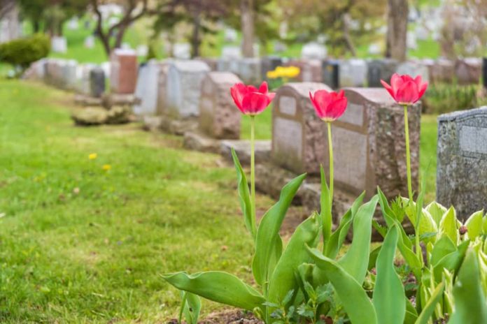 Banking On a Final Resting Place – Perpetual Care Cemeteries Must Operate By the Rules A funeral with flowers on the tombstones.