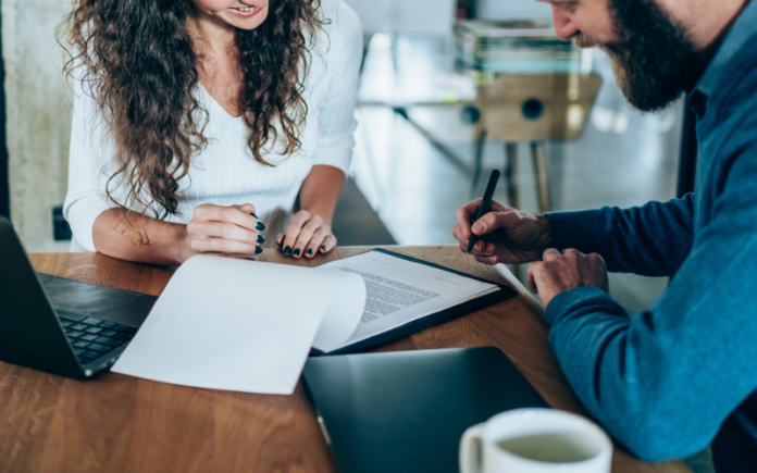 man and woman sitting at table signing forms man and woman sitting at table signing forms