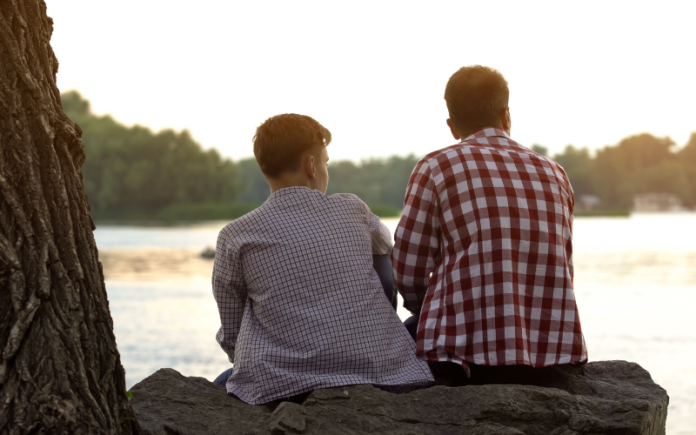 father and son sitting together outside