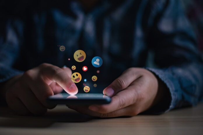 Man using smartphone sending emojis, diverse positive emoji coming out of mobile phone. Mobile application for chatting, creative image, Social media concept.