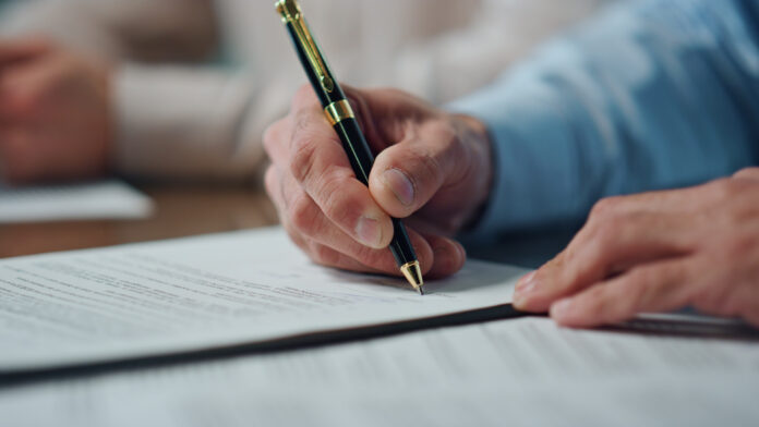 Close up of man's hand signing a will.