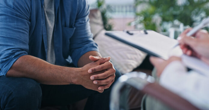Closeup shot of shot of an unrecognizable female therapist writing notes while in session with a male patient
