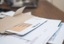 Debt After Death: Why Probate Strategy Matters Utility bill statement details, displaying due amount, alongside a phone calculator, set on a wooden apartment table. Financial responsibility in focus.