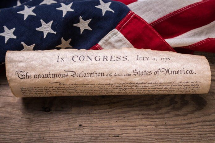 United States Declaration of Independence rolled in a scroll on a vintage American flag and rustic wooden board